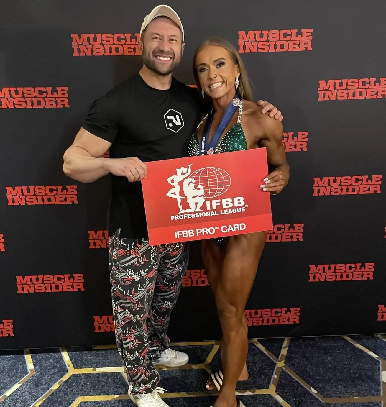 David DeMesquita with his athlete holding her IFBB Pro card at a Muscle Contest show