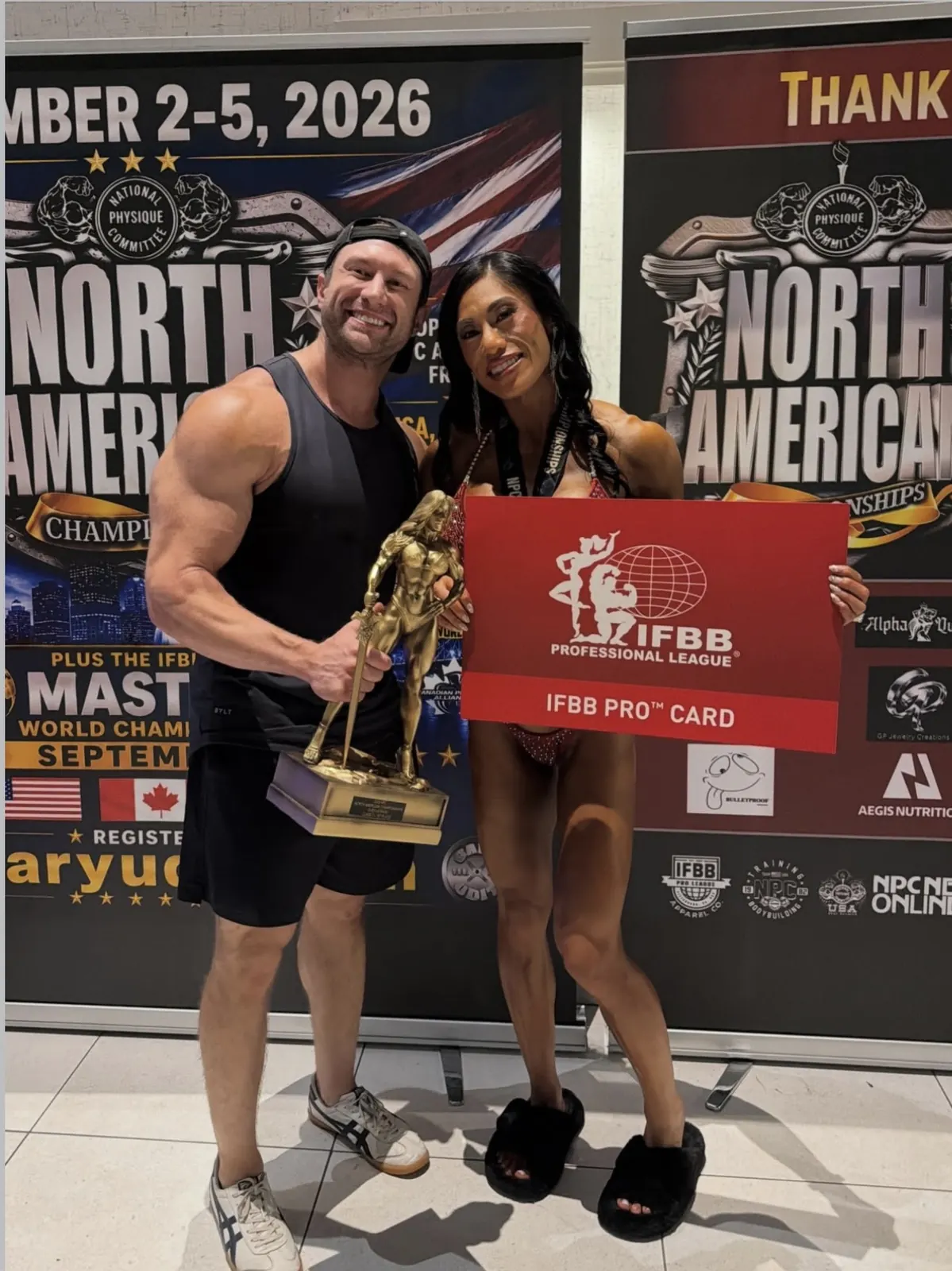 David DeMesquita with his athlete holding her IFBB Pro card at the NPC North Americans