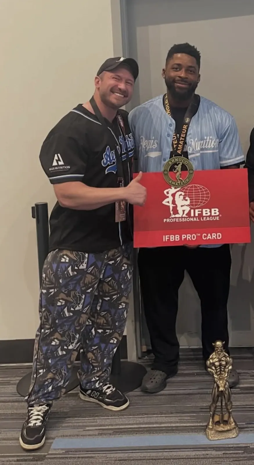David DeMesquita with his athlete holding her IFBB Pro card