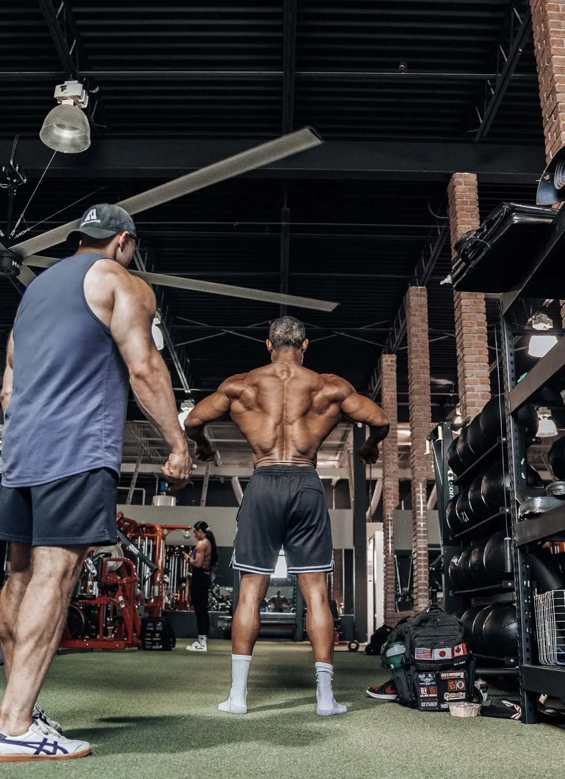 David DeMesquita checking an athlete’s back pose in the gym