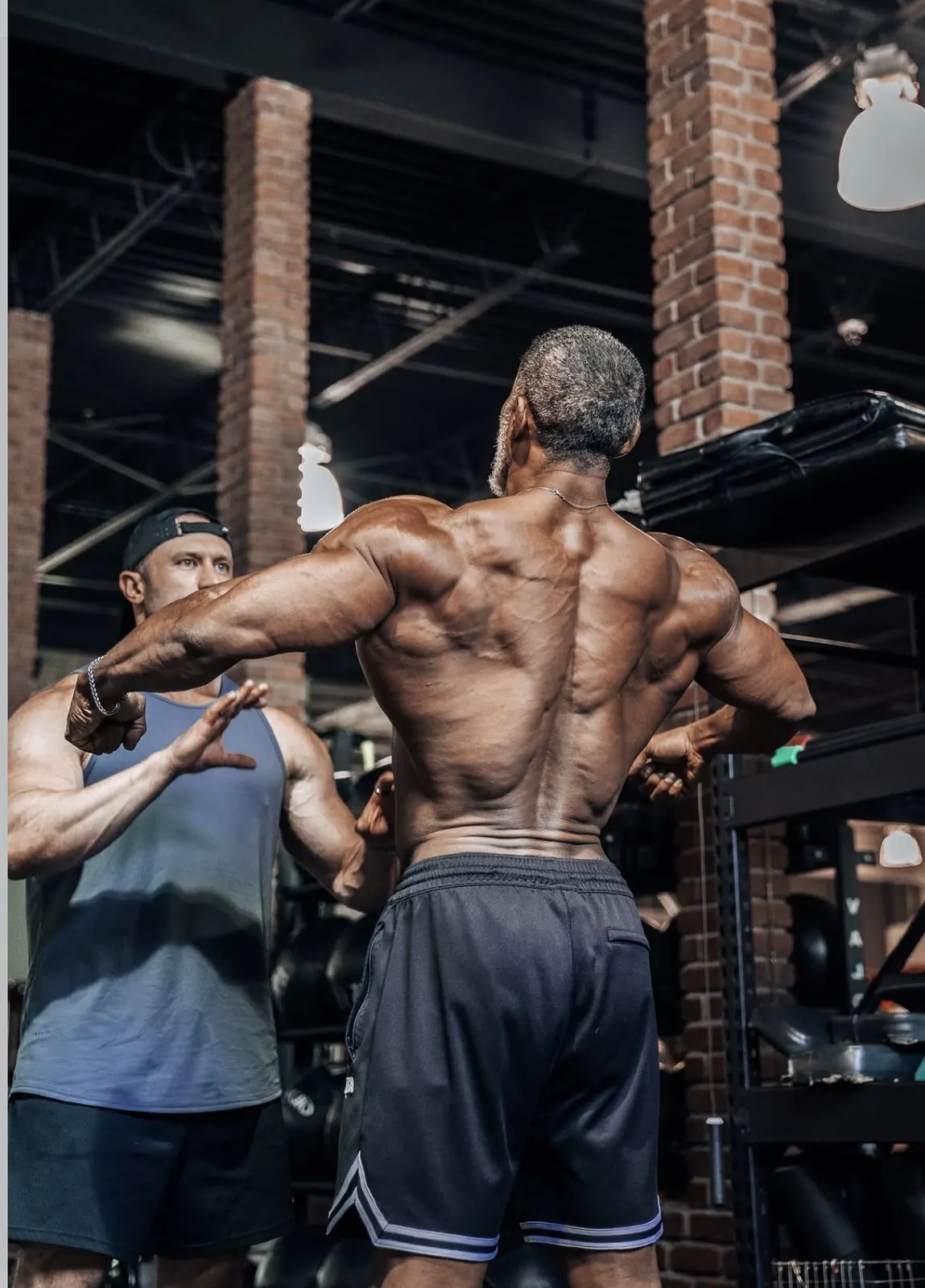 David DeMesquita reviewing an athlete’s back double biceps pose