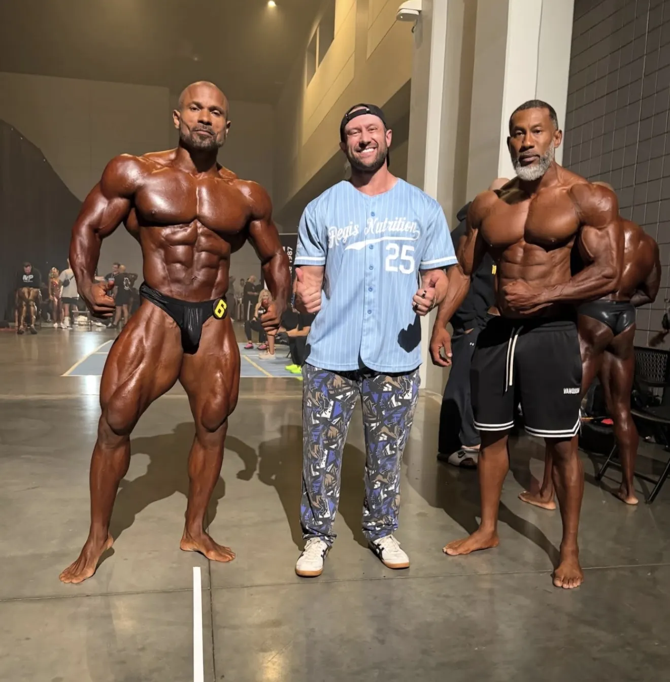 David DeMesquita between two of his bodybuilding athletes backstage